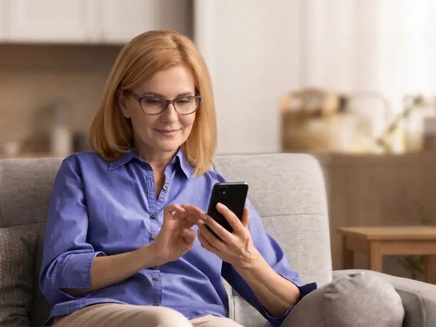 Kvinna i samtal med läkaren hemifrån soffan i sin telefon